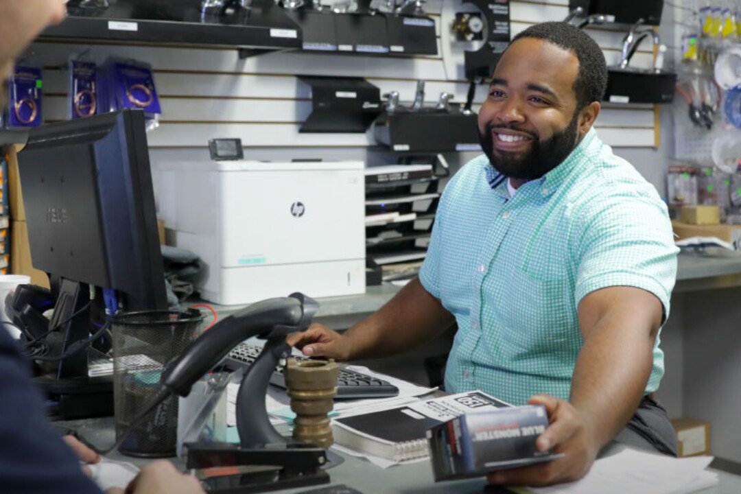 Smiling Hajoca teammate working the register at a sales counter